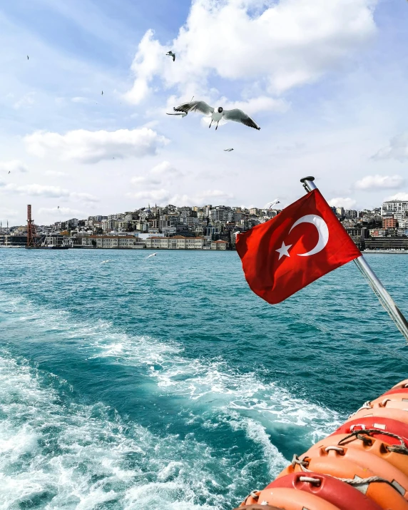 a flag on the back of a boat in the water, a colorized photo, pexels contest winner, hurufiyya, istanbul, youtube thumbnail, waving, 🚿🗝📝