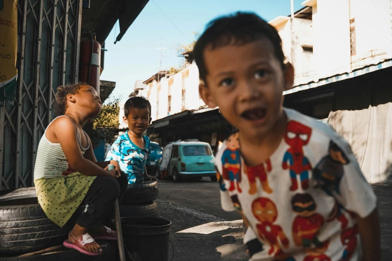 a couple of kids sitting on top of a pile of tires, pexels contest winner, graffiti, busy small town street, avatar image, thawan duchanee, excited