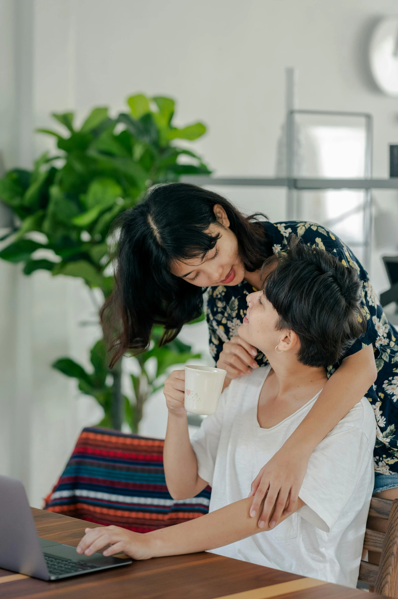 a man and woman sitting at a table in front of a laptop, by Jang Seung-eop, pexels contest winner, romanticism, sitting on a couch, lesbian embrace, asian female, product introduction photo