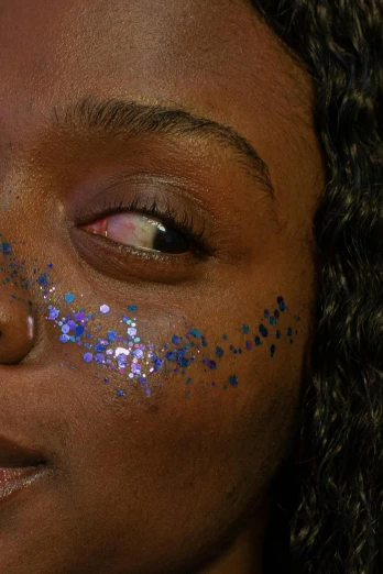 a close up of a woman with glitter on her face, an album cover, by Briana Mora, trending on pexels, afrofuturism, holo sticker, blue colored, sparse freckles, mole on cheek