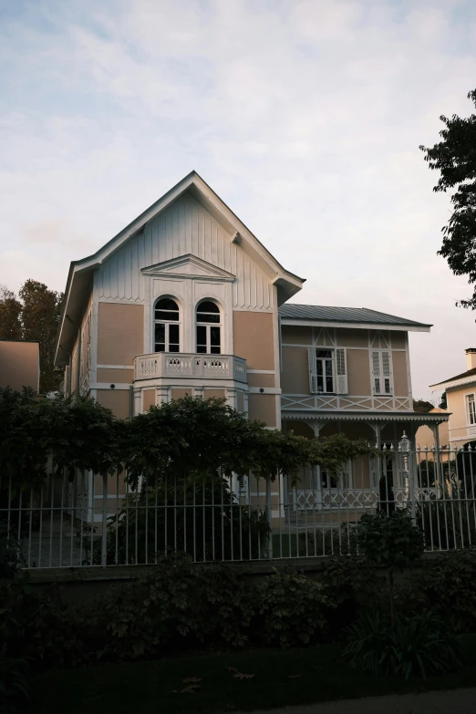 a house with a fence in front of it, inspired by Wilhelm Marstrand, art nouveau, in karuizawa, neoclassic, over-shoulder shot, during dawn