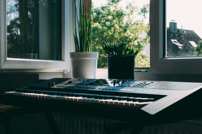 a keyboard sitting on top of a table next to a window, an album cover, unsplash, small plants on the window sill, devices and instruments, in a living room, profile picture 1024px