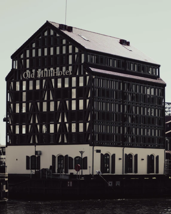 a black and white photo of a building next to a body of water, a colorized photo, unsplash, art nouveau, oh yeah, mill, cover image, architectural visualization