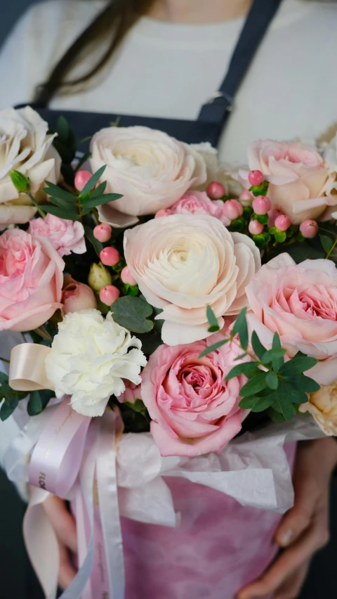 a woman holding a bouquet of pink and white flowers, soft colours scheme, laying on roses, no cropping, up close
