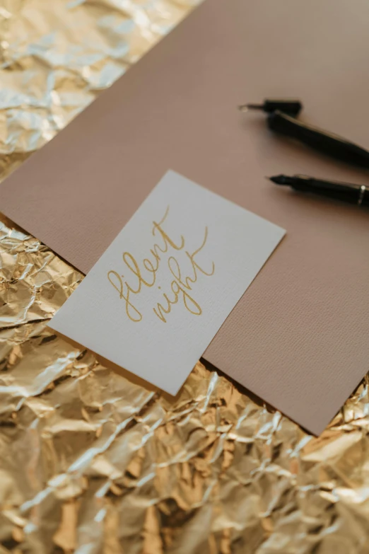 a pen sitting on top of a piece of paper, an album cover, by Grace Polit, pexels contest winner, gold foil, it's night, card template, calligraphy formula