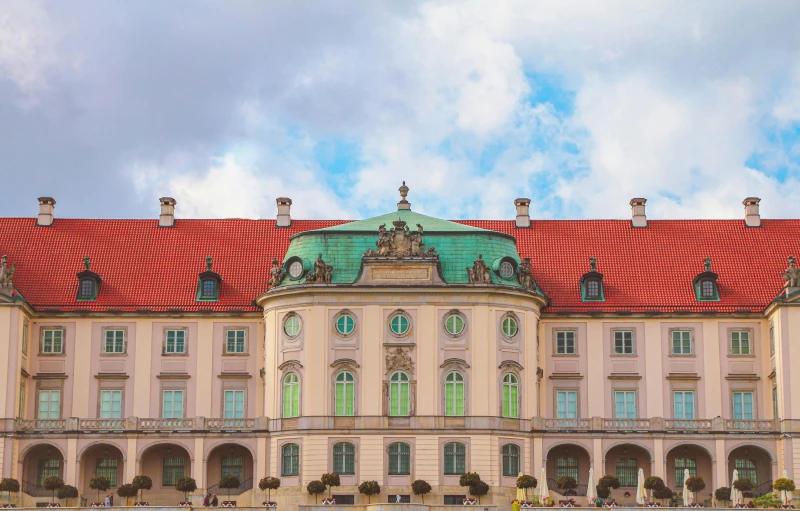 a large building sitting on top of a lush green field, an album cover, pexels contest winner, rococo, munich, colorful building, colonial, baroque color scheme