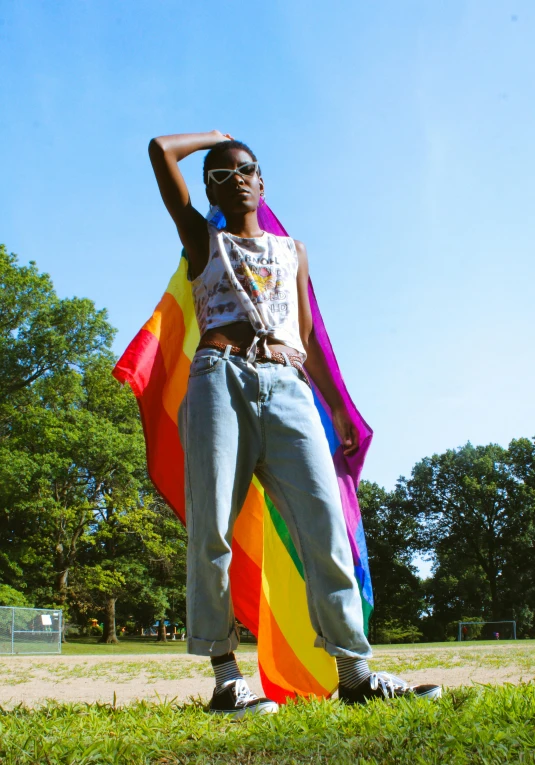 a man standing on top of a lush green field, an album cover, by Lily Delissa Joseph, happening, lgbt flag, playboi carti, pride parade, profile image