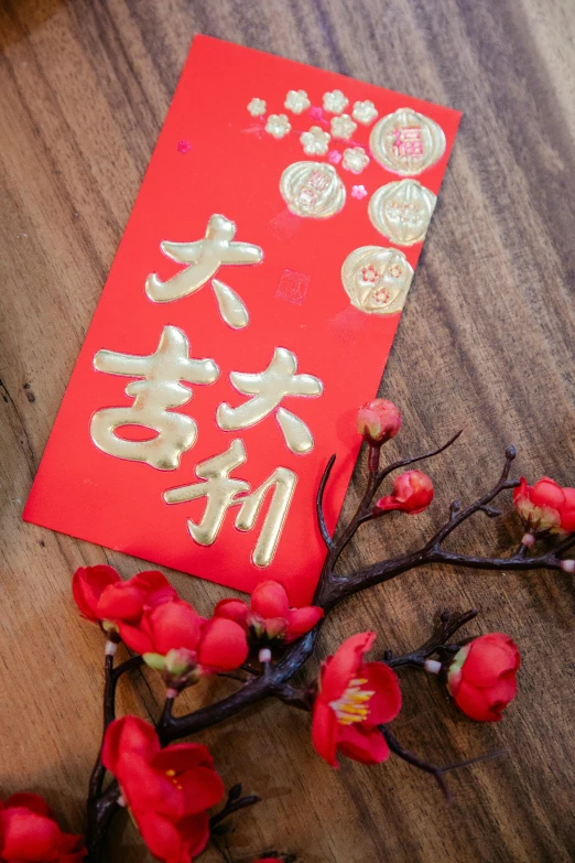 a red envelope sitting on top of a wooden table, gold flowers, thumbnail, hong kong, february)
