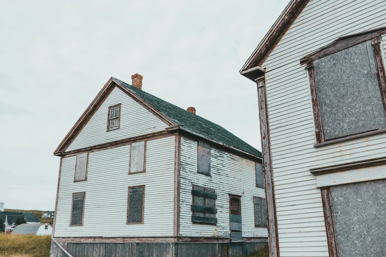 a couple of white houses sitting next to each other, a colorized photo, pexels contest winner, hyperrealism, inuit heritage, rusted silent hill, unsplash photo contest winner, boarded up