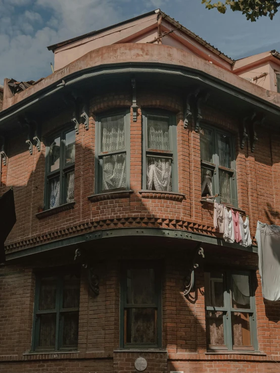 a red brick building with clothes hanging out to dry, a colorized photo, pexels contest winner, art nouveau, in disney, nepali architecture buildings, gif, cinematic detail