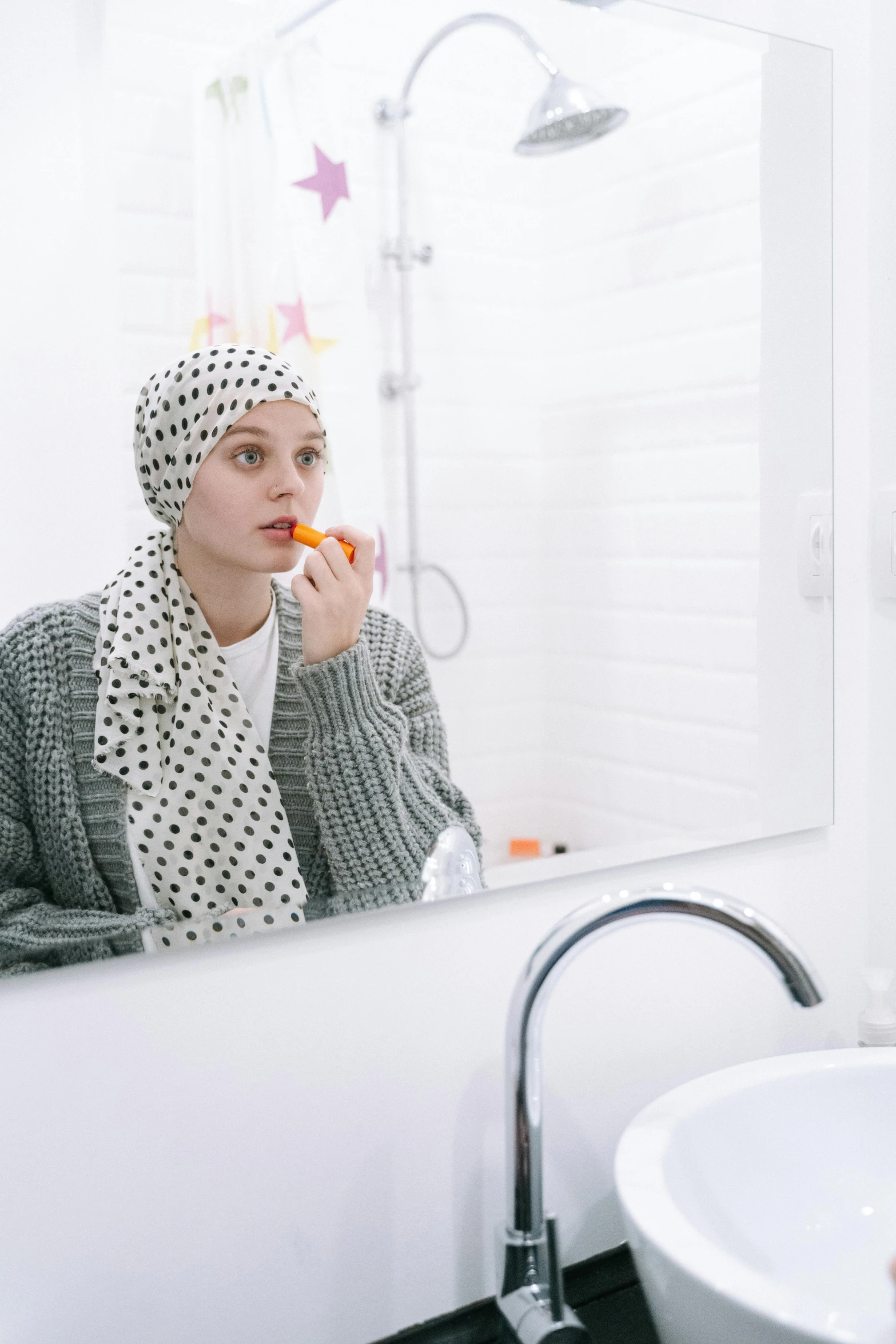 a woman brushing her teeth in front of a mirror, by Matija Jama, wearing a head scarf, gray and orange colours, polka dot, skincare