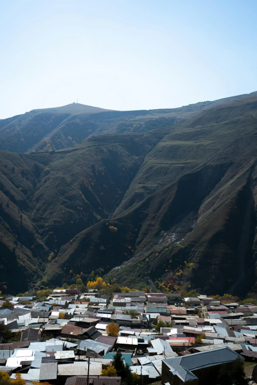 a view of a small town with mountains in the background, by Muggur, trending on unsplash, quito school, in between a gorge, 8k detail, tehran, autum