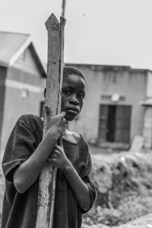 a black and white photo of a boy holding a pole, pexels contest winner, unmistakably kenyan, photo of the girl, in town, timid and vulnerable expression