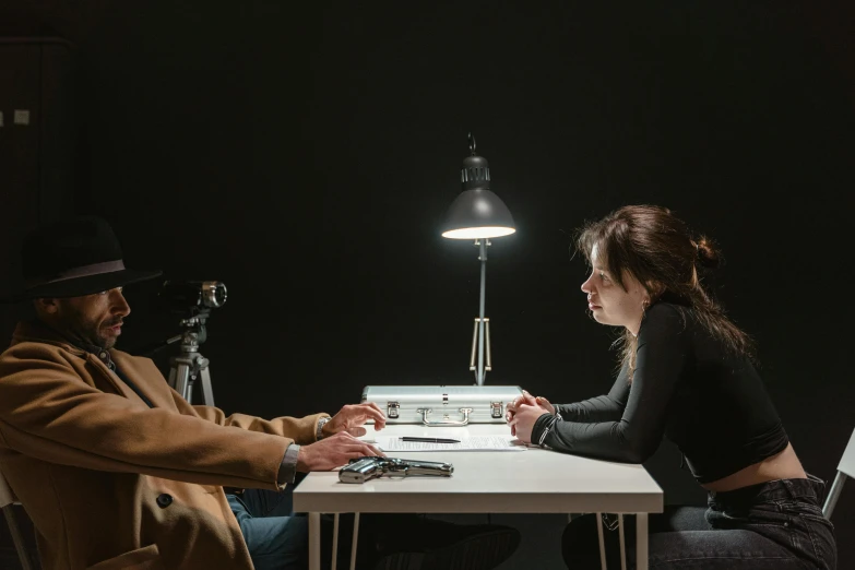 a man and a woman sitting at a table in front of a laptop, by Adam Marczyński, pexels contest winner, hyperrealism, dramatic lowkey studio lighting, lie detector test, from a movie scene, female investigator