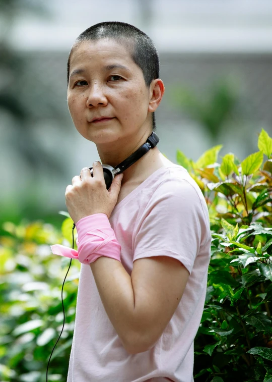 a woman standing in front of a bush with headphones on, inspired by Lin Tinggui, happening, wearing presidential band, pink, photograph credit: ap, bandage taped fists