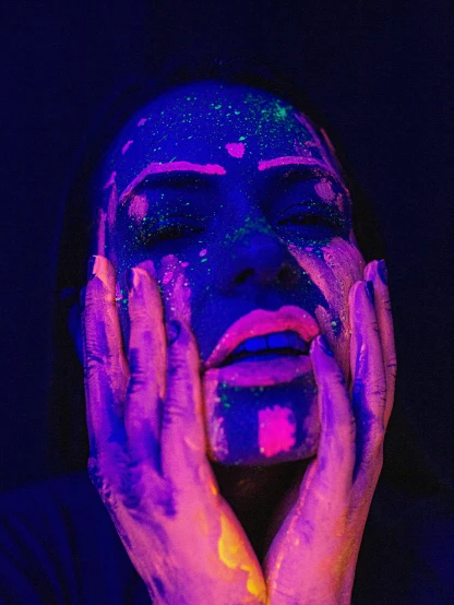 a close up of a person holding their hands to their face, an album cover, inspired by Elsa Bleda, trending on pexels, transgressive art, dripping in neon paint, black light rave, glitter gif, bisexual lighting