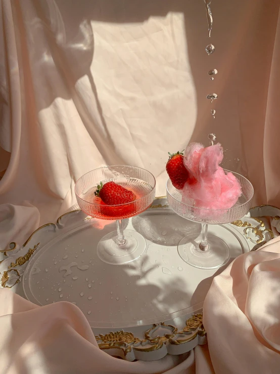 a couple of wine glasses sitting on top of a table, by Sydney Carline, romanticism, strawberry ice cream, 🎀 🧟 🍓 🧚, diaphanous translucent cloth, low quality photo