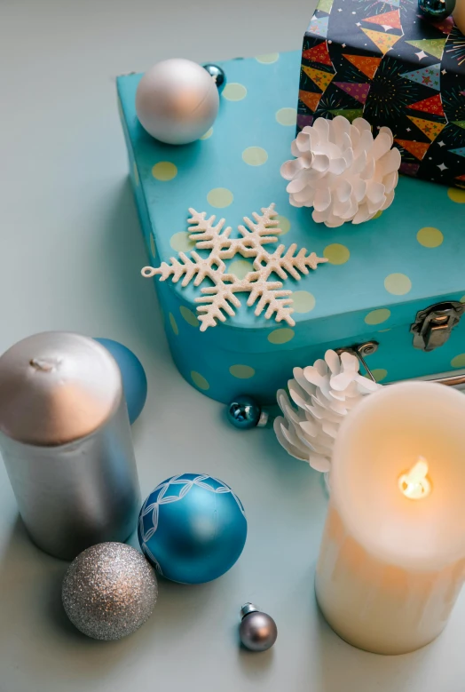 a blue gift box sitting on top of a table next to a lit candle, trending on pexels, folk art, snowflakes, high angle close up shot, lots of decoration and furniture, ilustration