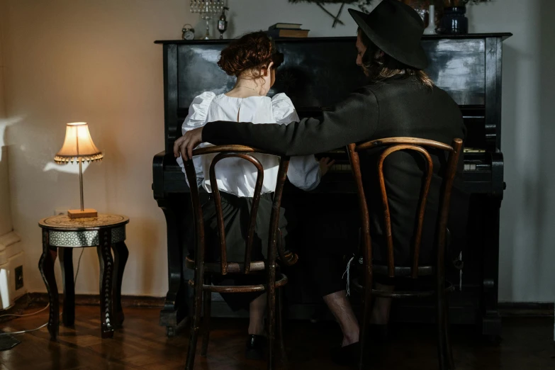 a man and a woman sitting at a piano, by Emma Andijewska, pexels contest winner, art nouveau, mourning family, sitting on chair, with his back turned, colonial style