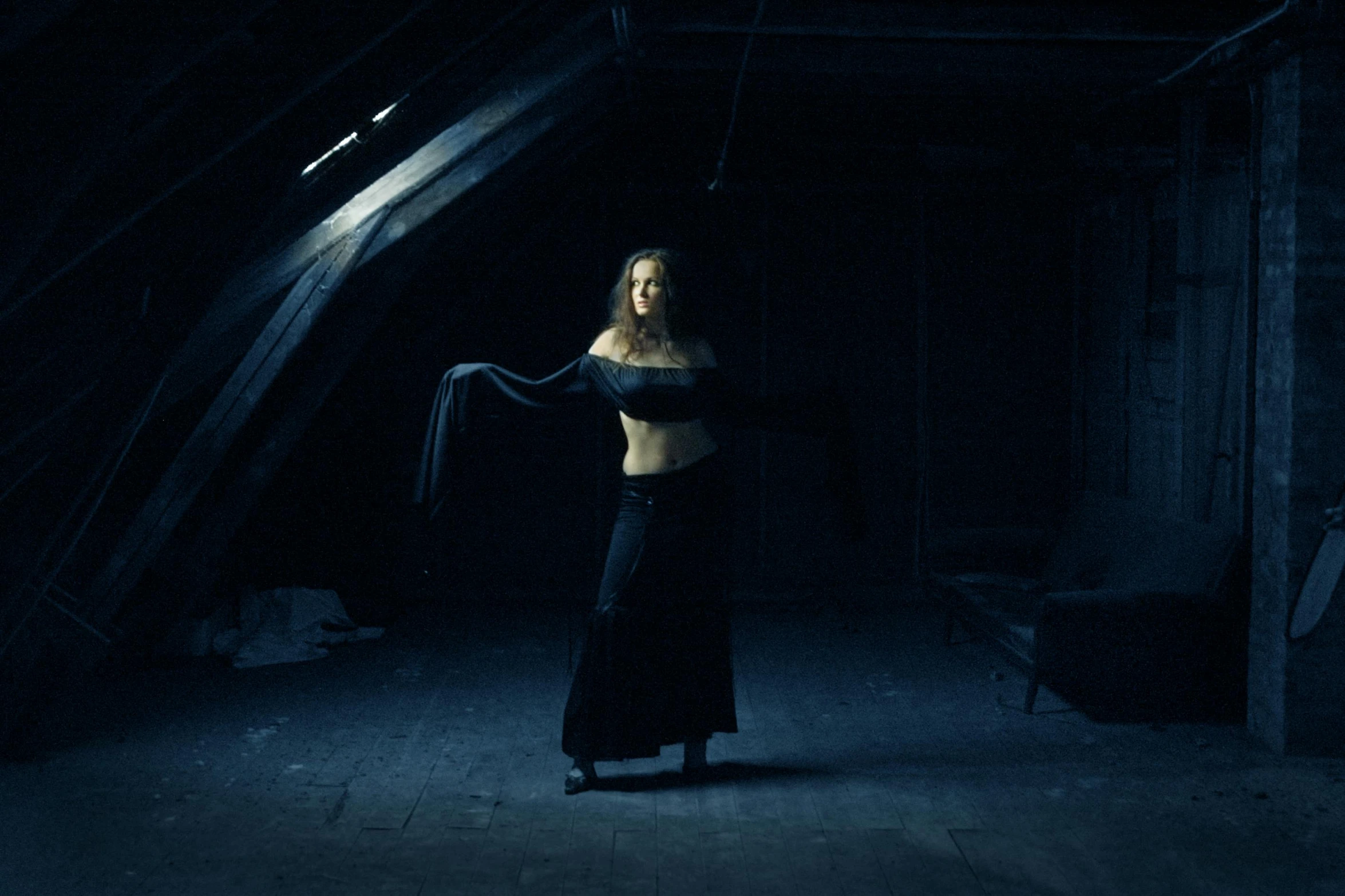 a woman in a black dress standing in a dark room, an album cover, inspired by Elsa Bleda, renaissance, belly dancing, witchcore clothes, in an attic, dark blue clothes