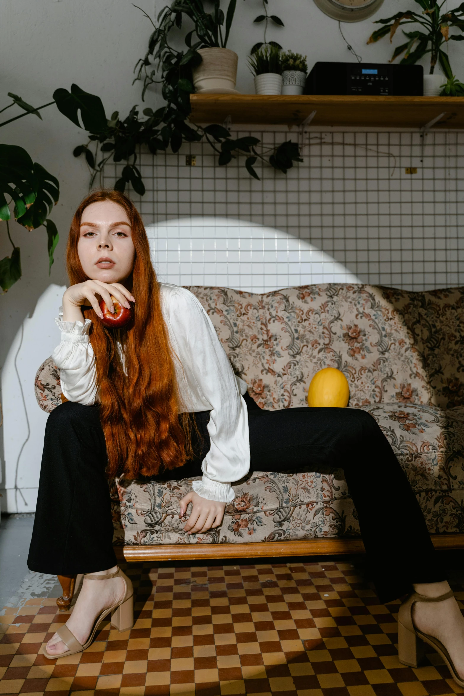 a woman with long red hair sitting on a couch, inspired by Elsa Bleda, trending on pexels, renaissance, wearing a lemon, teenager, androgynous person, standing in corner of room