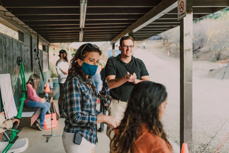 a group of people standing next to each other, wearing facemask, on set, miranda meeks, background image