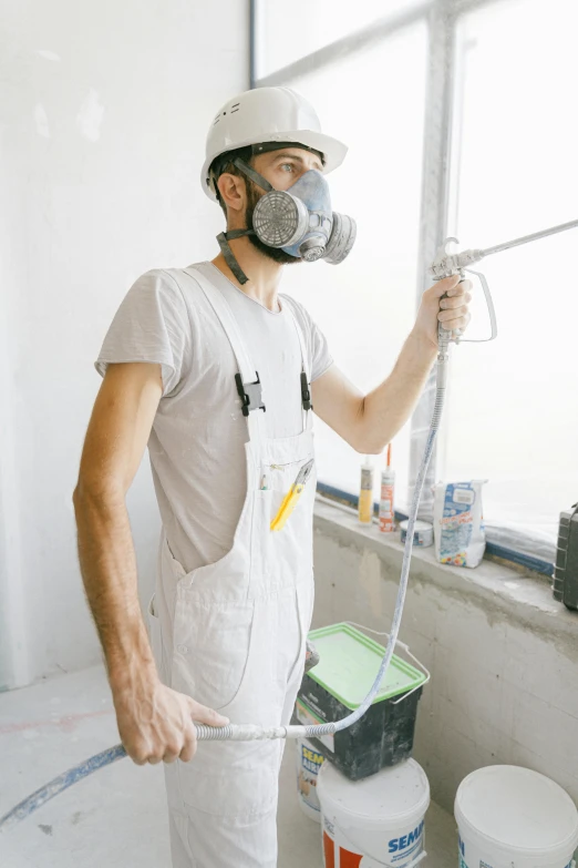 a man standing in a room holding a paint roller, an airbrush painting, pexels contest winner, dust mask, overalls, wearing a round helmet, profile image