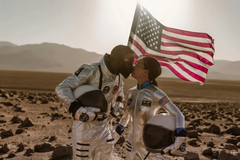 two astronauts kissing each other in front of an american flag, a colorized photo, by Romain brook, pexels contest winner, american romanticism, standing on a martian landscape, slide show, male and female, photoshoot