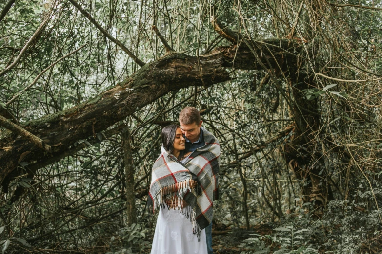 a man and woman standing next to each other in a forest, unsplash, romanticism, blanket, avatar image, overhanging branches, full shot photograph