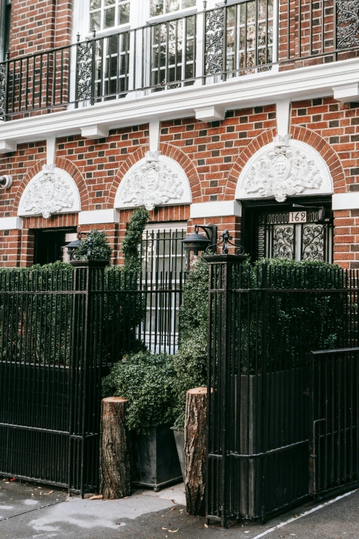 a black gate in front of a brick building, lush brooklyn urban landscaping, background image, multiple stories, ornate retreat