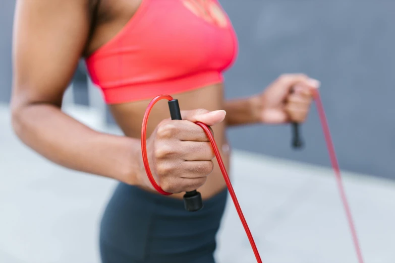 a close up of a person holding a jump rope, by Emma Andijewska, trending on pexels, hurufiyya, wearing red tank top, tubing, australian, hoses:10