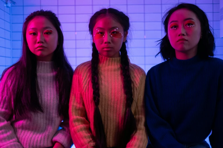 three women sitting next to each other in a room, an album cover, trending on pexels, neon backlit, asian descent, looking serious, braids
