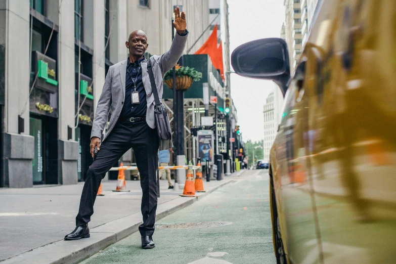 a man in a suit standing on the side of a street, by David Palumbo, pexels contest winner, happening, waving at the camera, lance reddick, taxi, worksafe. instagram photo