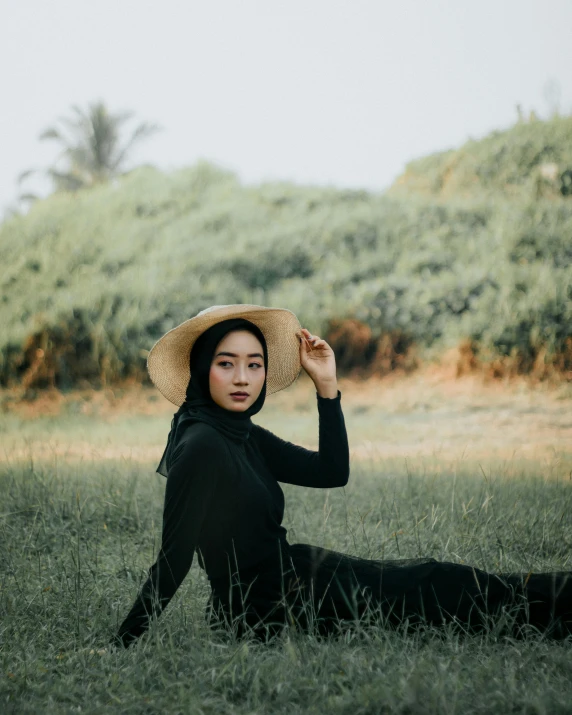 a woman sitting in a field wearing a hat, pexels contest winner, sumatraism, beautiful androgynous girl, black, malaysian, low quality photo