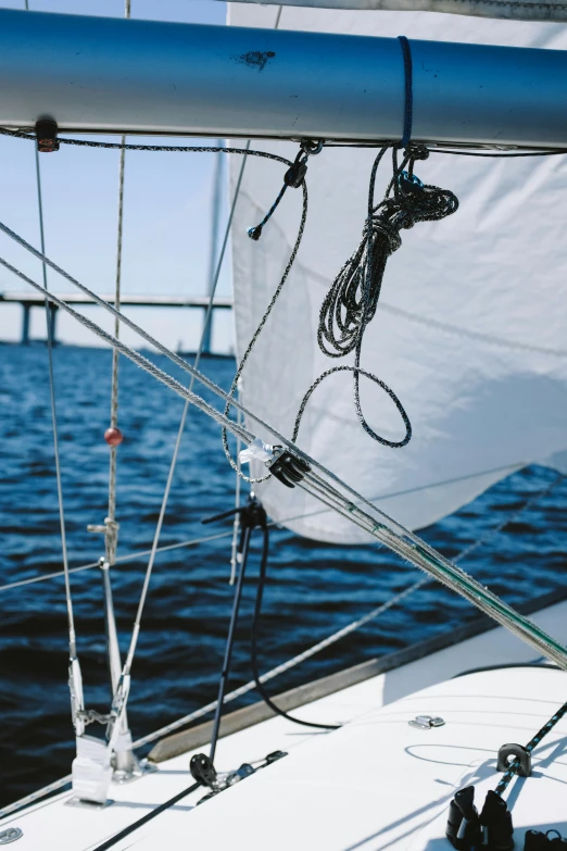 a sailboat on the water with a bridge in the background, wires and cords, up-close, overhead canopy, seams