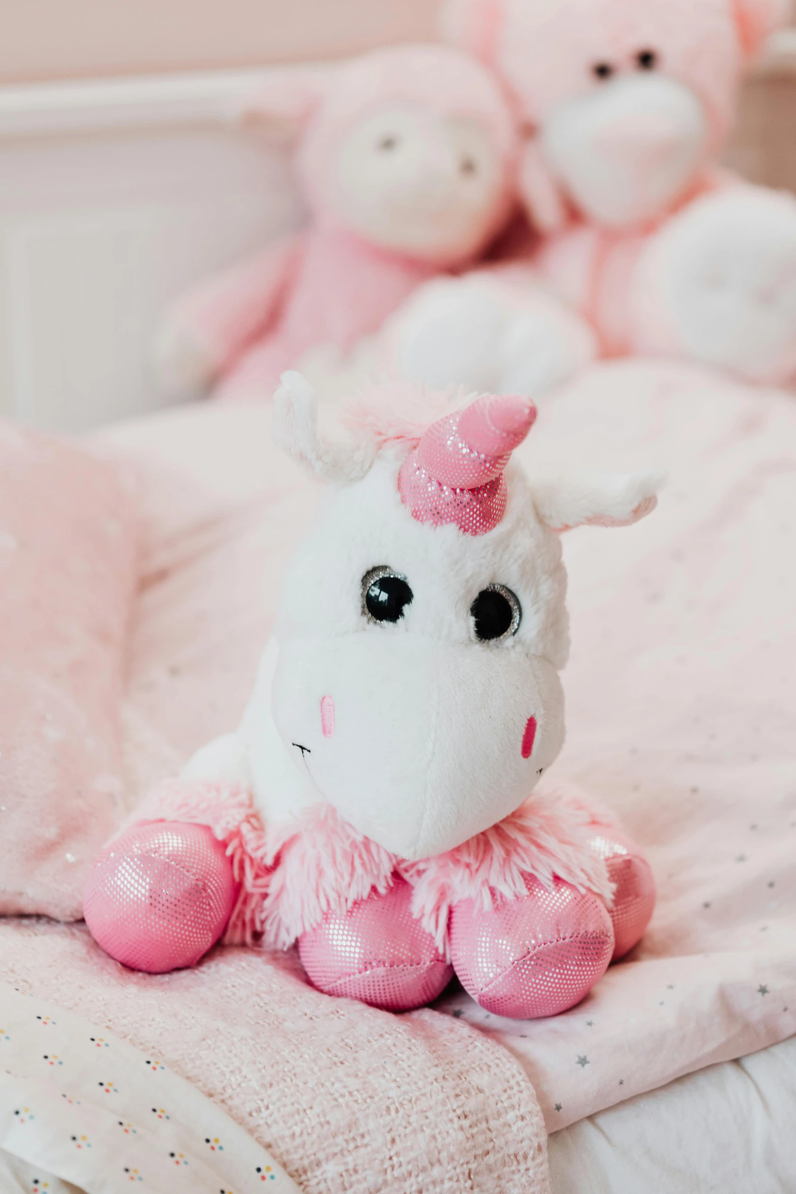 a group of stuffed animals sitting on top of a bed, pink nose, white unicorn, bedazzled, closeup of an adorable