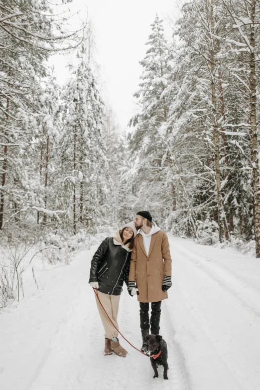 a man and woman walking a dog in the snow, by Zofia Stryjenska, pexels contest winner, romanticism, in front of a forest background, 🚿🗝📝