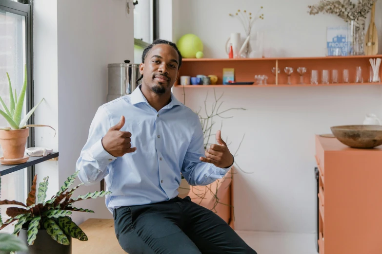 a man sitting in front of a window giving a thumbs up, by Washington Allston, pexels contest winner, arbeitsrat für kunst, a black man with long curly hair, in an office, sitting in a lounge, various posed