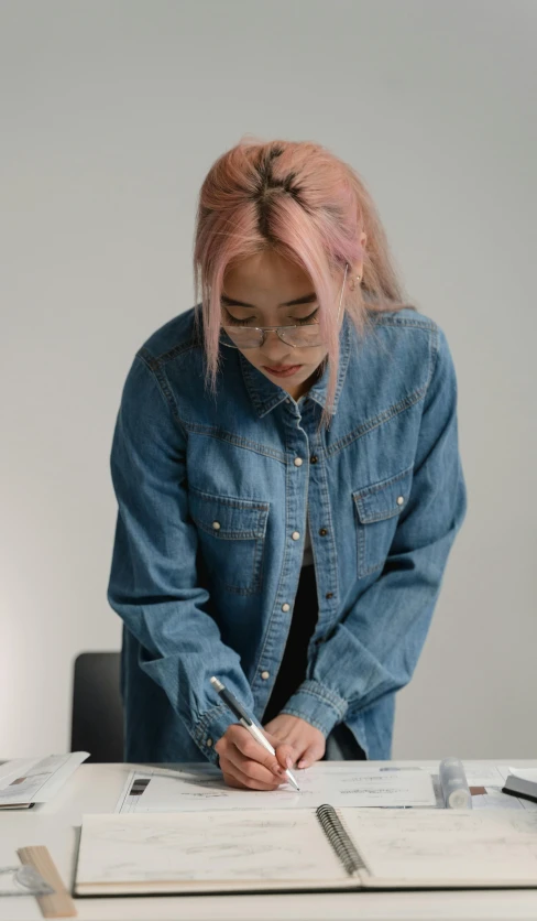 a woman sitting at a table writing on a piece of paper, an album cover, inspired by Elsa Bleda, trending on pexels, hyperrealism, denim jacket, cinematic outfit photo, asian female, pixar portrait 8 k photo