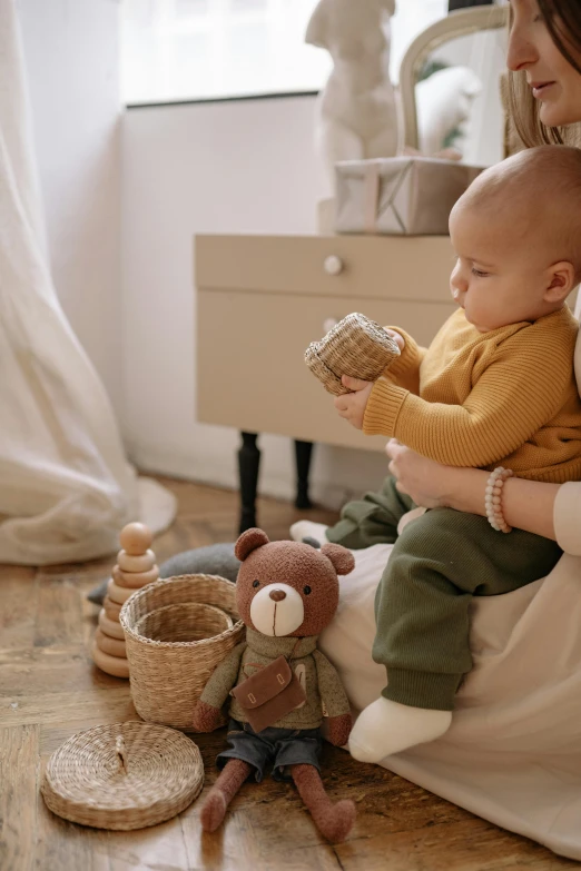 a woman sitting on a bed holding a baby, pexels contest winner, kids toys, natural materials, inspect in inventory image, medium shot of two characters