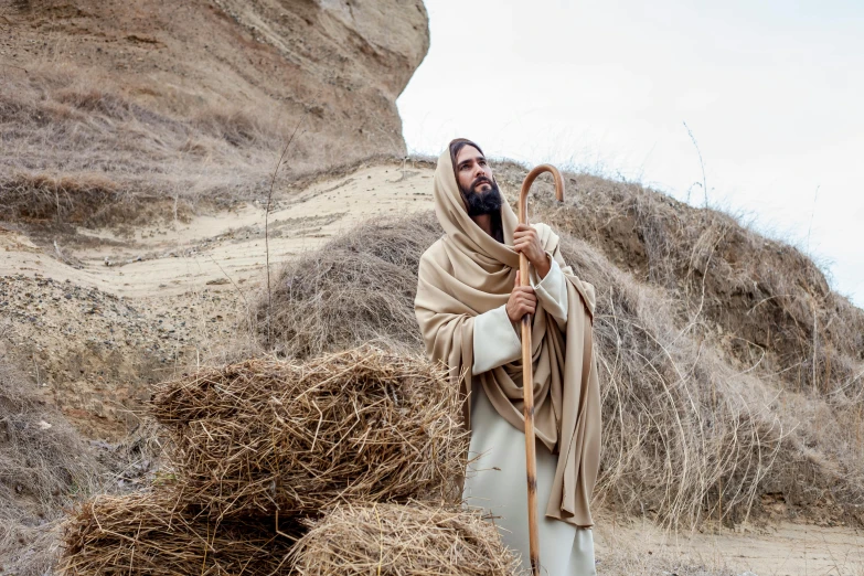 a man standing next to a pile of hay, inspired by Andrei Rublev, pexels, renaissance, dressed like jesus christ, shepherd's crook, standing on rocky ground, slide show