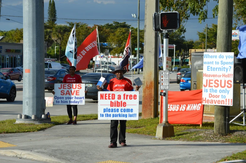 a group of people holding signs on the side of a road, florida man, red banners, outside in parking lot, slide show