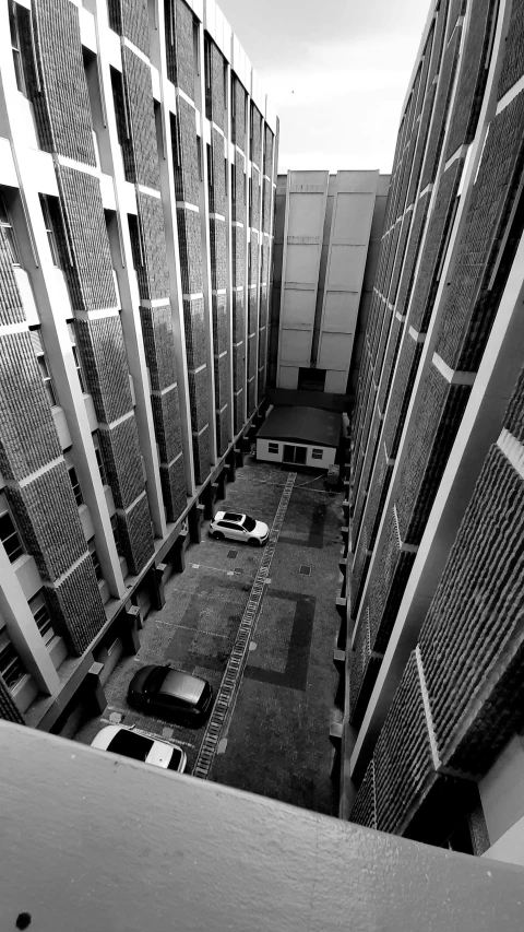 a black and white photo of a building, a black and white photo, inspired by Thomas Struth, unsplash, cars parked, alleys, view from high, prison complex