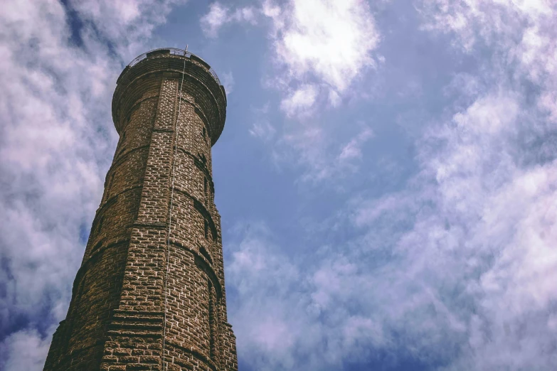 a tall brick tower sitting under a cloudy blue sky, unsplash, hurufiyya, ventilation shafts, light house, 2 0 0 0's photo