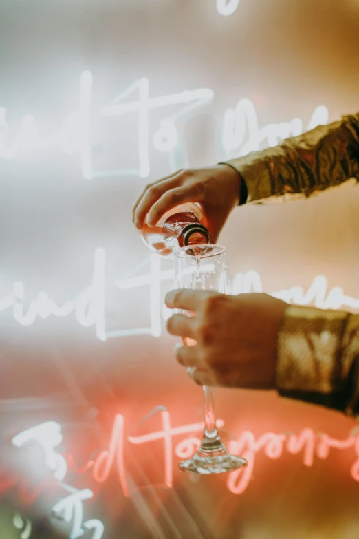 a close up of a person holding a wine glass, interactive art, bright signage, champagne, backdrop, romance