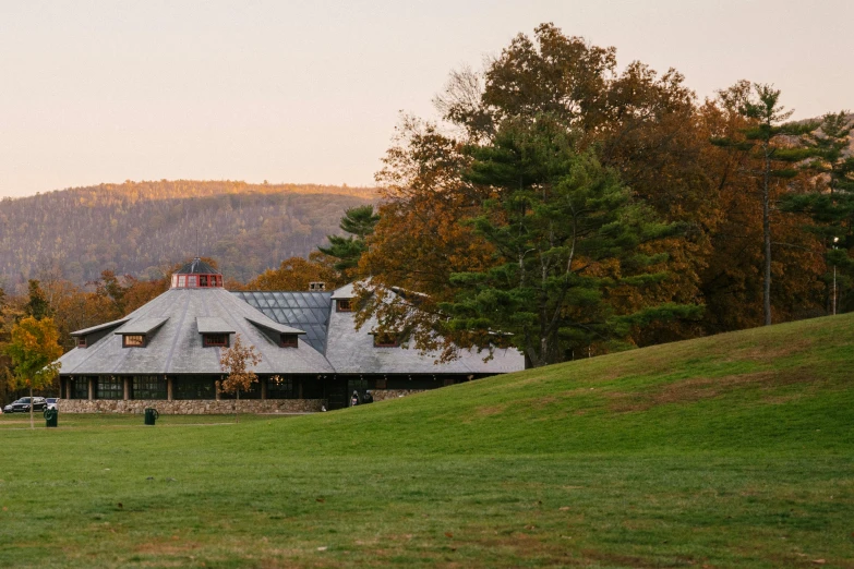 a house sitting on top of a lush green field, american barbizon school, fall foliage, pavilion, honeycomb halls, warmhole