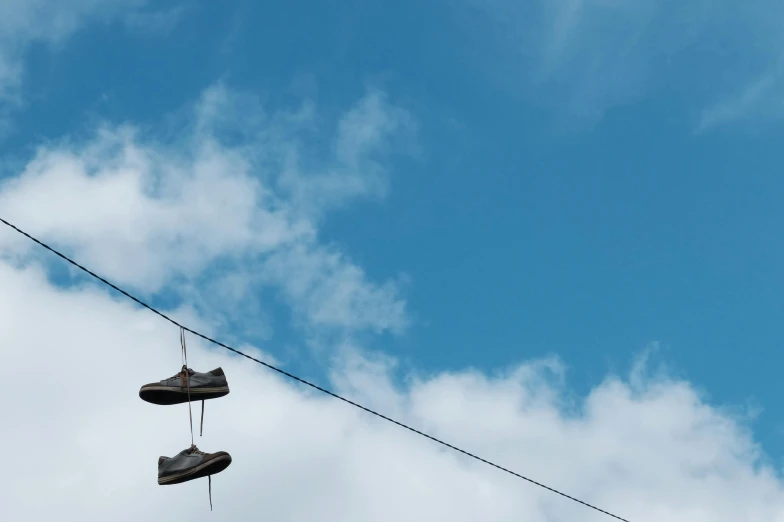 a pair of shoes hanging from a power line, unsplash, light blue sky with clouds, multiple stories, slides, plain background