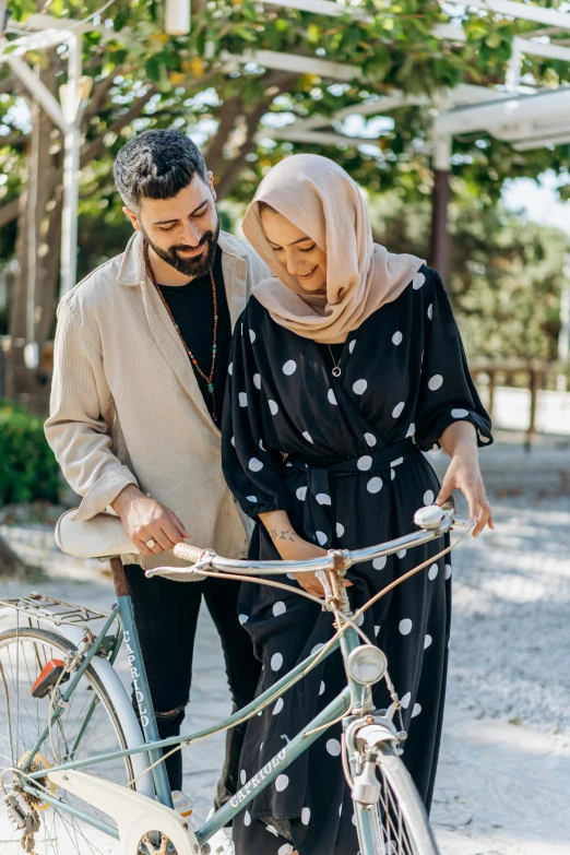 a man and a woman standing next to a bicycle, hijab, supportive, subtle detailing, millennial vibes