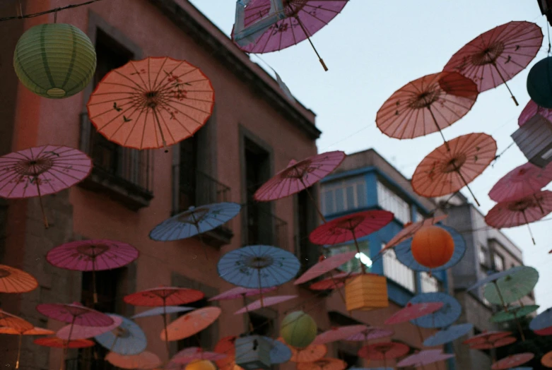 a bunch of umbrellas hanging from the side of a building, chinese lanterns, guanajuato, street photo, illustration »