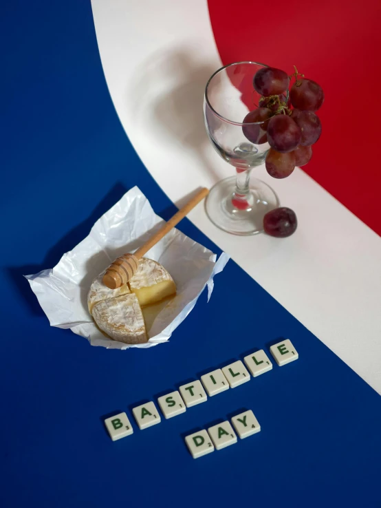 a piece of bread sitting on top of a table next to a glass of wine, flag, day time, pastelle, slide show